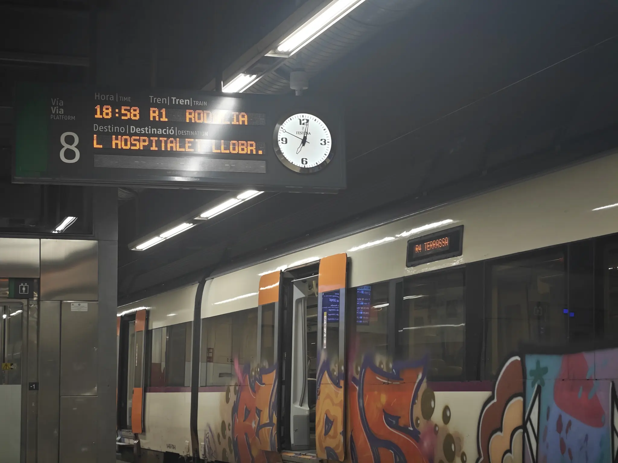 graffitied Rodalies 447 in Sants with "R4 Terrassa" on its displays, while the platform indicators say "R1 L'Hospitalet Llobr."