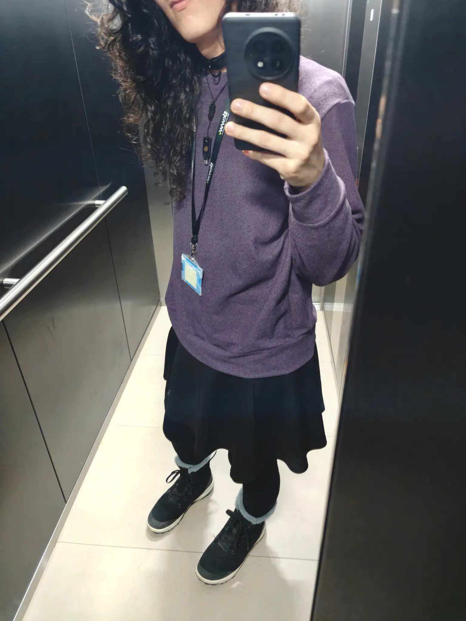 me alone at my office's elevator wearing a purple sweater, a black skirt, and black stockings