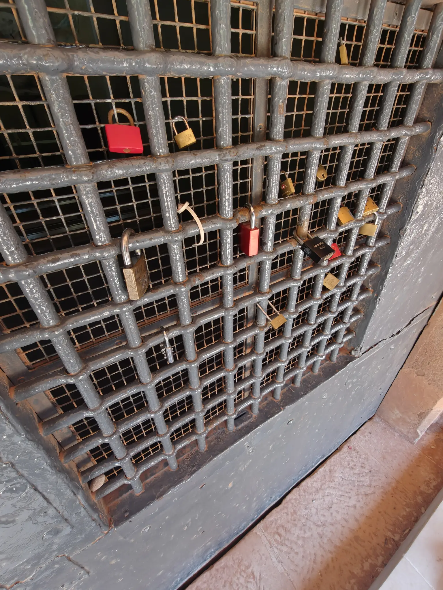 an old iron door with a bunch of "love locks" in it